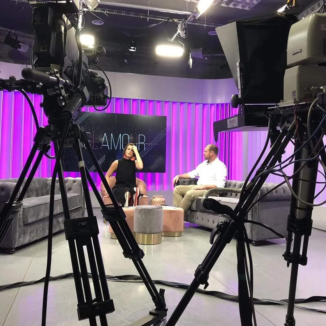 Set de televisión visto detrás de las cámaras: Felipe Bozzo, sentado en un sillón, es entrevistado por una conductora