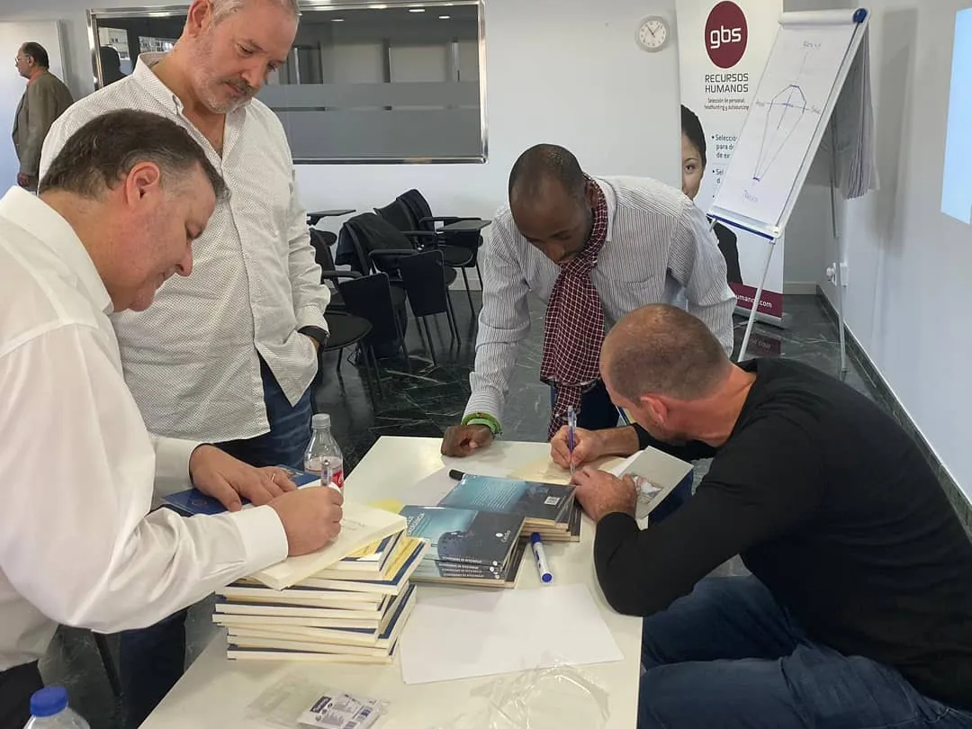 Felipe Bozzo firma ejemplares de su libro en una mesa, rodeado de asistentes, en Valencia