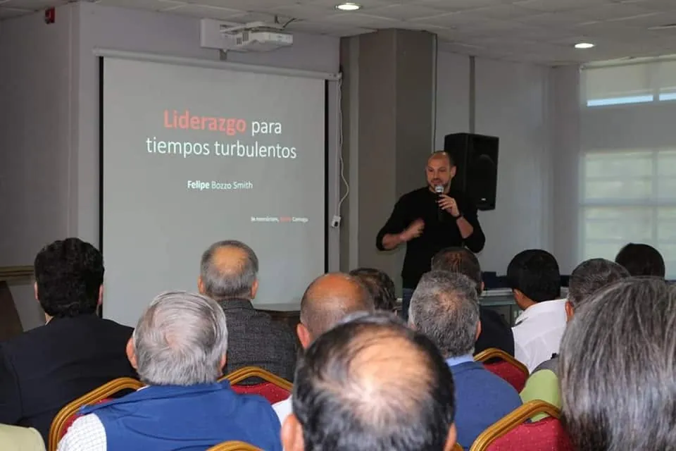 Felipe Bozzo expone ante el público, junto a la diapositiva «Liderazgo para tiempos turbulentos»